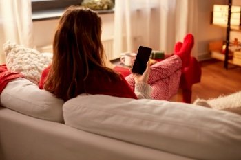christmas  winter holidays and leisure concept - young woman using smartphone at cozy home woman using smartphone at home on christmas