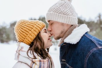 people  love and leisure concept - happy man kissing woman rsquo;s nose in winter forest happy man kissing woman rsquo;s nose in winter