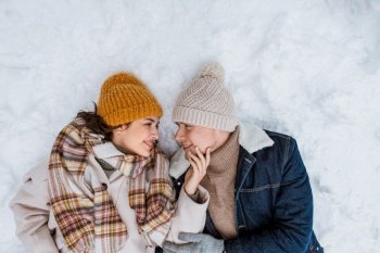 people  love and leisure concept - happy smiling couple lying on snow in winter happy smiling couple lying on snow in winter