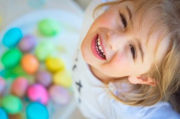 Portrait of a cute little baby boy looking up with happiness and hope Playing with colorful eggs Eggs hunting Happy holidays Happy Children on Ea