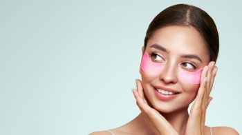 A young beautiful smiling woman with cosmetic patches on her eyes Cosmetic procedures skin care around the eyes Perfect healthy facial skin