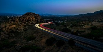 A high angle shot of yellow and red lights on the highway surrounded by rocks at night High angle shot of yellow and red lights on the highway surrou
