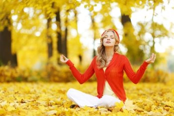Yoga woman sitting in lotus position in autumn park