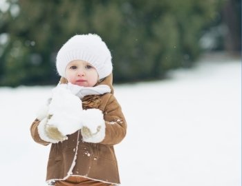 Baby playing with snow in winter park