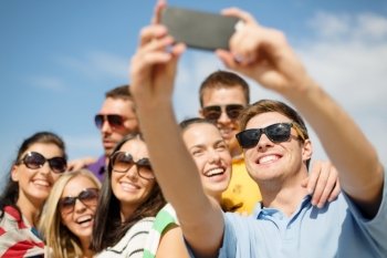 summer  holidays  vacation and happiness concept - group of friends taking picture with smartphone