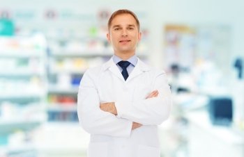 medicine  pharmacy  people  health care and pharmacology concept - smiling male pharmacist in white coat over drugstore background