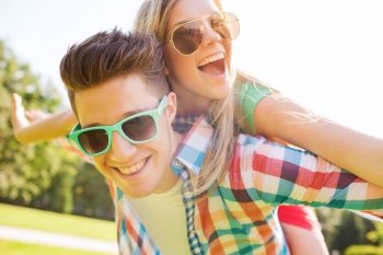 holidays  vacation  love and friendship concept - smiling teen couple in sunglasses having fun in summer park