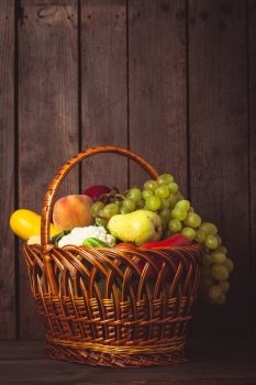 Basket of vegetables and fruits over wooden background