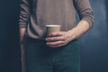 Young man is  holding a brown paper cup