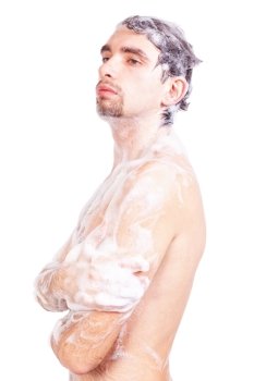 Young naked man taking a shower in the foam with a beautiful body isolated on white background