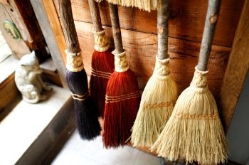 Old fashioned brooms hanging against a wooden wall Handmade Brooms