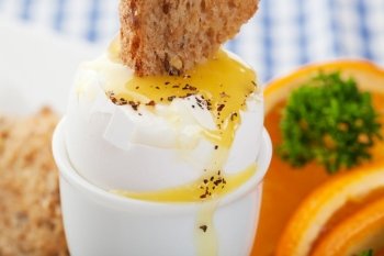 Toast dipped into the warm  runny  yolk of a soft boiled egg