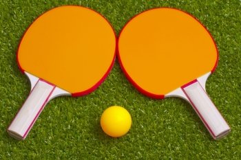 Two ping pong rackets with an orange ball