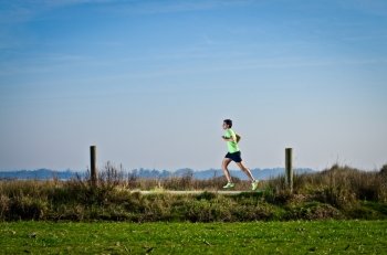 Male runner at sprinting speed training for marathon outdoors on country landscape