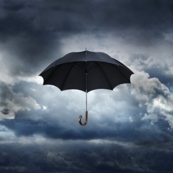 Old black umbrella against rainy sky