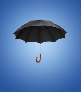 Old black vintage umbrella against blue background