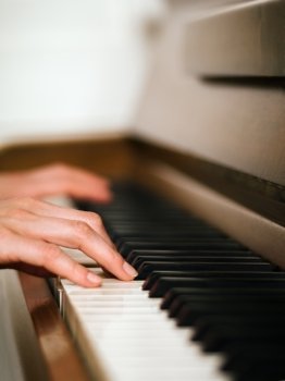 Photo of female hands playing an upright piano Very shallow depth of field with focus on fingers  xA;